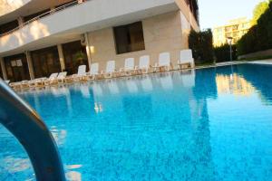 a large swimming pool with white chairs in a building at Eden - Menada Apartments in Sunny Beach