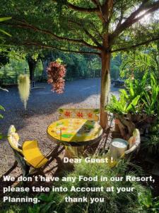 un tavolo da picnic e una panca sotto un albero di Baandin resort a Sukhothai