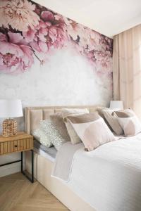 a bedroom with a bed with pink flowers on the wall at APARTAMENT BOHO in Gdańsk