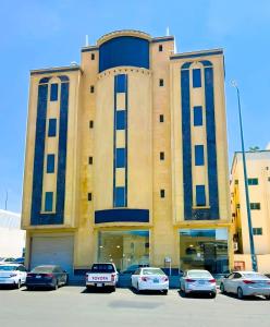 un grand bâtiment avec des voitures garées dans un parking dans l'établissement فيو بلس للشقق الفندقية, à Khamis Mushait