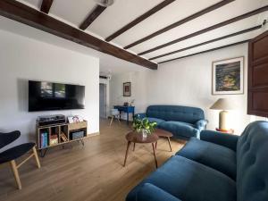 een woonkamer met blauwe banken en een tv bij Entretinas - Natural Stays Pechón in Pechón