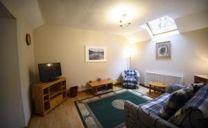 a living room with a couch and a tv at Bramble Cottage in Ollach