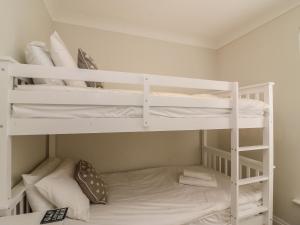two bunk beds in a small room with a bed at Castle Cove Cottage in Weymouth