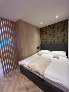 1 dormitorio con 1 cama grande y pared de madera en APARTMÁN STYLE Brezno en Brezno