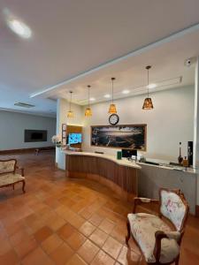 a lobby with a waiting area with two chairs and a clock at Hotel Violeta in Guarapari