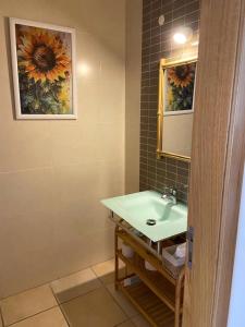 a bathroom with a sink and a painting of a sunflower at Maura's Holiday House in Silveira