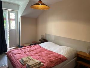een slaapkamer met een roze en wit bed en 2 dekens bij La maison du jardin in Saint-Jean-de-Luz