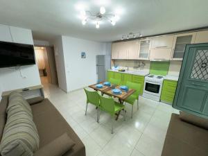 a living room with a table and a kitchen with green cabinets at Antoaneta's apartment in Kalamitsi