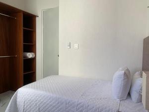 1 dormitorio con 1 cama con sábanas y almohadas blancas en Departamento en riviera Maya, en Tulum