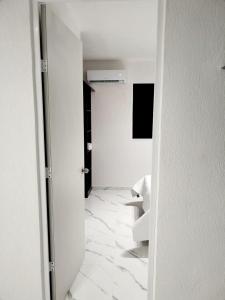 Habitación con un pasillo con paredes blancas y suelo de mármol. en Departamento en riviera Maya, en Tulum