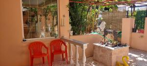 two red chairs sitting next to a building with windows at LENA'S SWEET HOME in Artemida