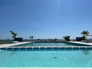 a swimming pool with turquoise water and palm trees at The Peninsula Resort in Mamburao