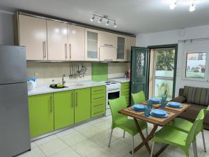 a kitchen with green cabinets and a table with green chairs at Antoaneta's apartment in Kalamitsi