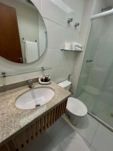 a bathroom with a sink and a toilet and a mirror at Hotel Violeta in Guarapari