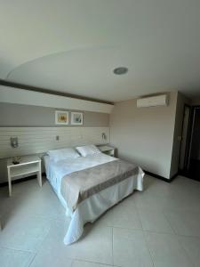 a bedroom with a large bed and a table at Hotel Violeta in Guarapari