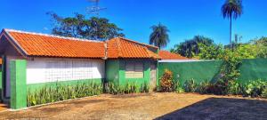 a green and white house with an orange roof at Pousada Recanto das Maritacas in Brotas