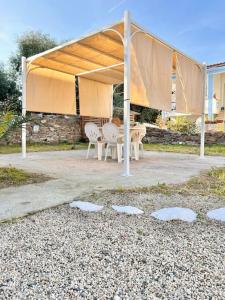 a pavilion with chairs and a table under a tent at Casetta Bianca con Giardino in Posada