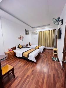 1 dormitorio con 2 camas y suelo de madera en KHÁCH SẠN PHƯƠNG DUNG, en Dak Rơleang