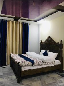 a bedroom with a large bed with blue curtains at LeGrand Hotel & Resort in Swat