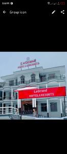 a large white building with a red sign on it at LeGrand Hotel & Resort in Swat