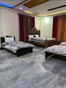 twee bedden in een kamer met rode gordijnen bij LeGrand Hotel & Resort in Swat