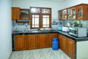 a kitchen with wooden cabinets and a microwave at Onara Guest in Anuradhapura