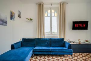 ein blaues Sofa im Wohnzimmer mit Fenster in der Unterkunft MONZA centro-Milano [Casa di Fronte alla Stazione] in Monza