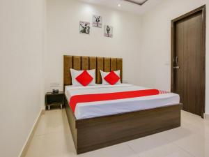 1 dormitorio con 1 cama grande con almohadas rojas en Super OYO Hotel Orchid Regency en Ludhiana