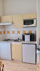 uma cozinha com electrodomésticos brancos e um micro-ondas em Résidence Les Iles Britanniques em La Bourboule