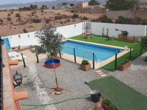 uma piscina com uma árvore e um parque infantil em 2 bed cottage Lorca many hiking & cycling trails em Lorca