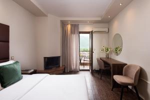 een hotelkamer met een bed, een bureau en een televisie bij Hotel Naiades in Órma