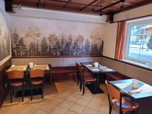 un restaurante con mesas y sillas y una pintura en la pared en Garni B&B Mozart Nesthouse, en Canazei