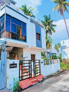 una casa blanca con palmeras en el fondo en Rose Villa, en Pondicherry