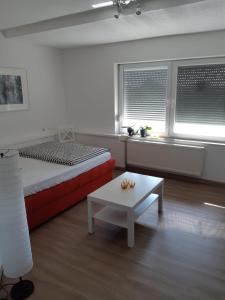 a bedroom with a bed and a table and two windows at Apartman River in Prijedor