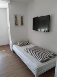 a bed with a flat screen tv on a wall at Apartman River in Prijedor