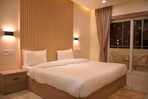 una camera da letto con un grande letto bianco e una finestra di Spruce Hill Hotel & Restro a Nainital