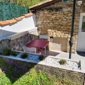 a garden with a table and chairs in front of a stone building at Les Pierres de Cézaire in Saint-Cézaire-sur-Siagne