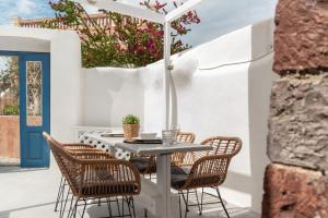 a table with chairs and an umbrella on a patio at ArcadOIA House in Oia