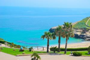 a view of a beach with palm trees and the ocean at Arborea Studio Apartment in Porto Torres