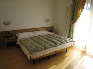 duże łóżko w sypialni z oknem w obiekcie Garni B&B Mozart Nesthouse w mieście Canazei