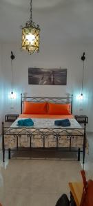 a bedroom with an orange bed and a chandelier at MAISON ISOLA DI ORTIGIA in Siracusa