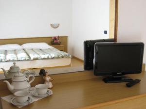 1 dormitorio con 1 cama, TV y set de té en Garni B&B Mozart Nesthouse, en Canazei