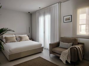 1 dormitorio con 1 cama y 1 silla en Bond Smart Living Suites, en Atenas