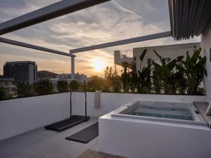 bañera de hidromasaje en un balcón con vistas a la puesta de sol en Bond Smart Living Suites, en Atenas