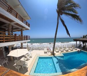 een zwembad met een palmboom en de oceaan bij Bungalows Playa Bonita in Máncora