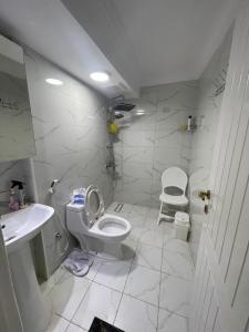a white bathroom with a toilet and a sink at منتجع ريف خزيمة - الفيروز in Al Madinah