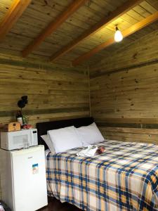 a bed in a room with a wooden wall at Cabanas Luar adaptada in São Francisco de Paula