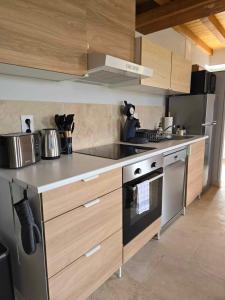 una cocina con electrodomésticos de acero inoxidable y armarios de madera en Gite au pied de la Colline en Vézelay