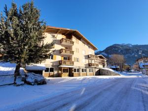 a snow covered road in front of a building at Garni B&B Mozart Nesthouse in Canazei