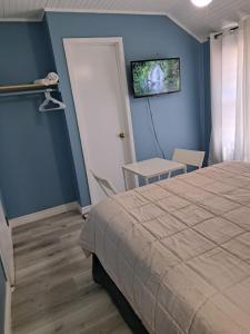 1 dormitorio con 1 cama y TV en la pared en Windspire Inn, en Port Elgin